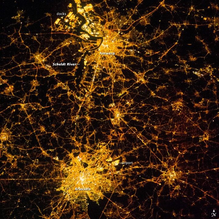 A NASA ISS satellite image of Belgium at night, highlighting Brussels, Antwerp, major transport corridors, and port facilities illuminated by low pressure sodium (LPS/SOX) street lighting. The characteristic amber glow reflects decades of nationwide adoption driven by the technology’s industry-leading luminous efficacy, low energy consumption, strong visibility in fog-prone and maritime environments, and reduced light pollution compared with many broad-spectrum lighting systems.